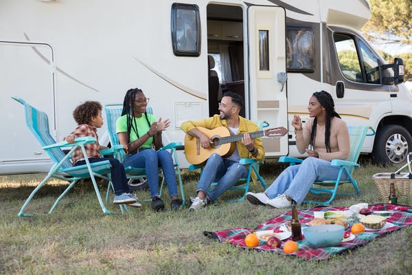 Group of people having fun sat outside a caravan - Buying Caravan Insurance